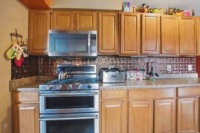 kitchen featuring light stone counters, decorative backsplash, and stainless steel appliances