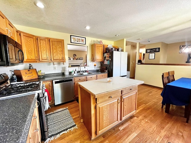 352 Valleybrook Cir, Howard, OH 43028 - kitchen with appliances with stainless steel finishes, a sink, a textured ceiling, light wood-style flooring, and a kitchen island