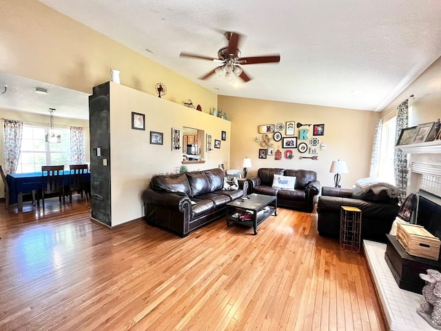 352 Valleybrook Cir, Howard, OH 43028 - living area with light wood-style flooring, ceiling fan, a fireplace, vaulted ceiling, and a textured ceiling