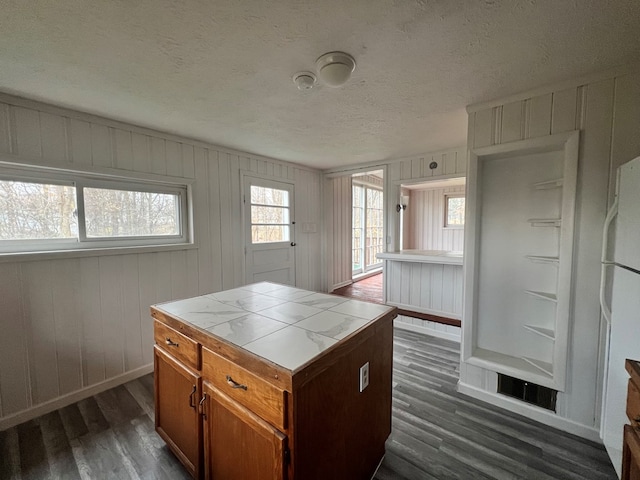 kitchen featuring a textured ceiling, tile counters, a kitchen island, and dark hardwood / wood-style floors