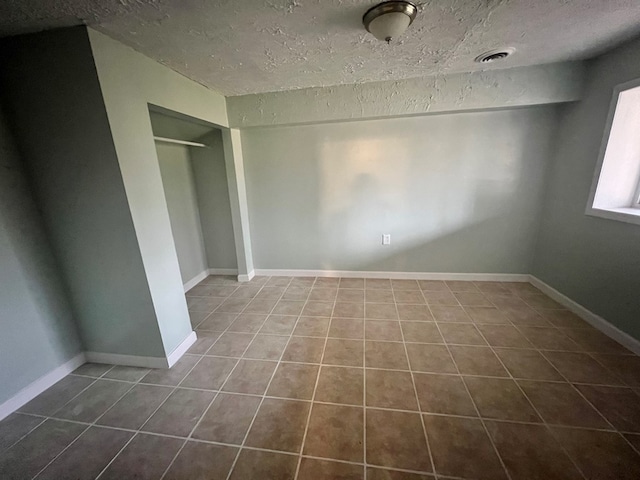 unfurnished bedroom with tile patterned floors, a closet, and a textured ceiling