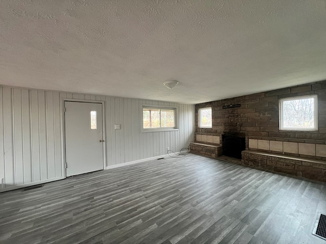 unfurnished living room featuring wood-type flooring, a textured ceiling, and plenty of natural light