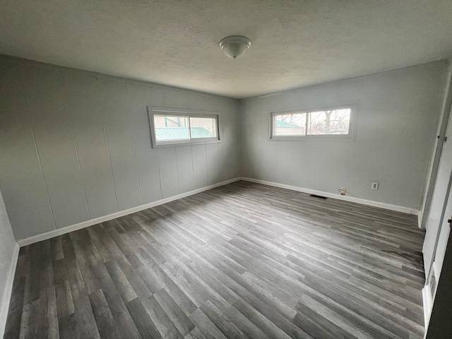 unfurnished room featuring dark hardwood / wood-style flooring and a textured ceiling