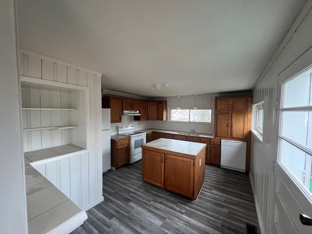 kitchen featuring a center island, white appliances, sink, built in features, and tile counters