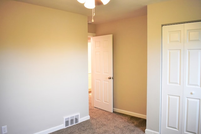 unfurnished bedroom featuring dark carpet and a closet