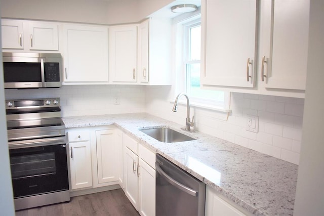 kitchen featuring white cabinets, decorative backsplash, stainless steel appliances, and sink