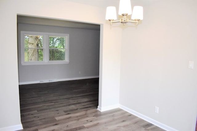 empty room with hardwood / wood-style floors and an inviting chandelier