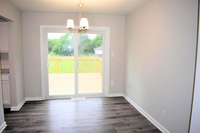 unfurnished dining area with a chandelier and dark hardwood / wood-style floors