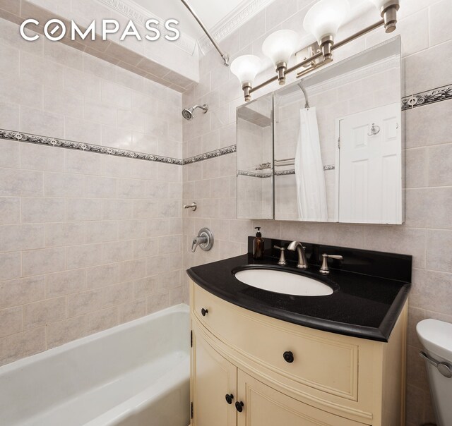 full bathroom featuring vanity, tile walls, toilet, shower / tub combo with curtain, and crown molding