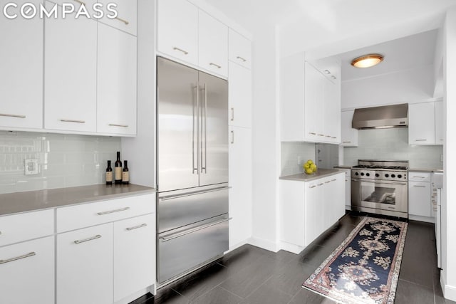 kitchen with white cabinetry, wall chimney range hood, tasteful backsplash, and high end appliances