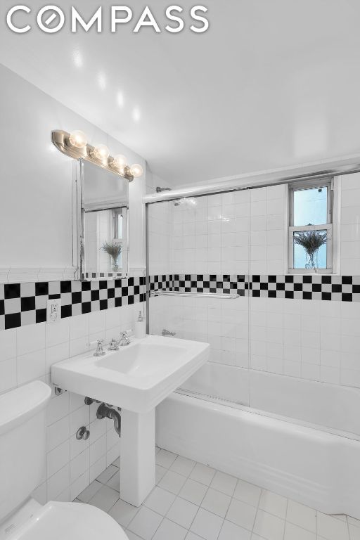 bathroom featuring toilet, tile walls, and tiled shower / bath