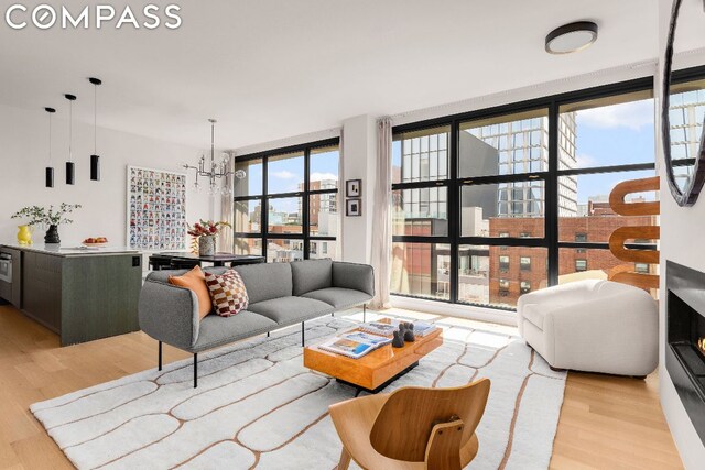 living room with a notable chandelier, floor to ceiling windows, and light hardwood / wood-style floors