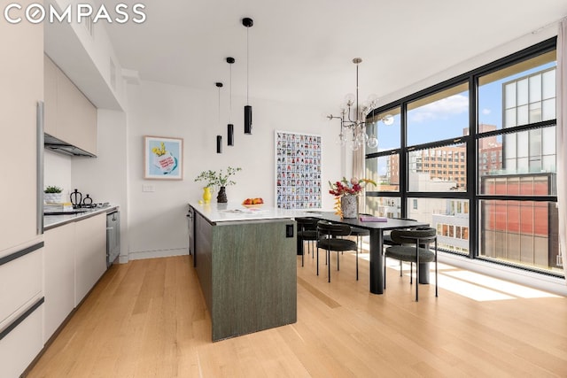 kitchen with hanging light fixtures, a notable chandelier, white cabinetry, and light hardwood / wood-style floors