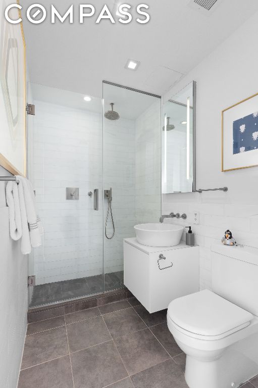 bathroom with an enclosed shower, vanity, and toilet