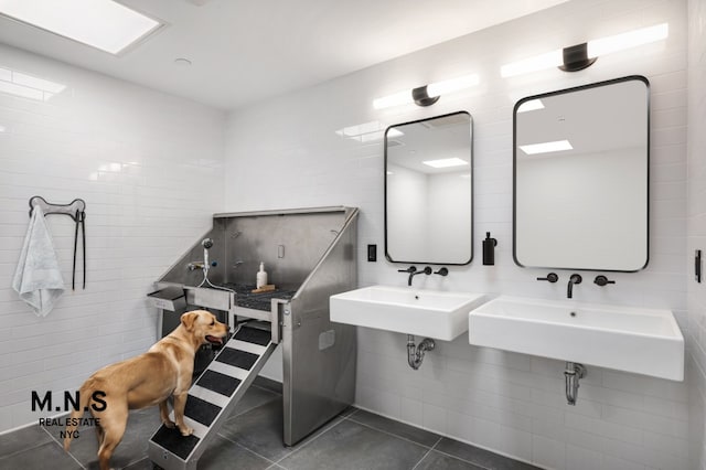 misc room with tile walls, dark tile patterned flooring, and a sink