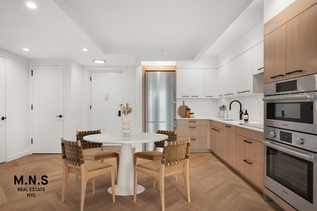 kitchen with a sink, light brown cabinets, stainless steel appliances, recessed lighting, and modern cabinets