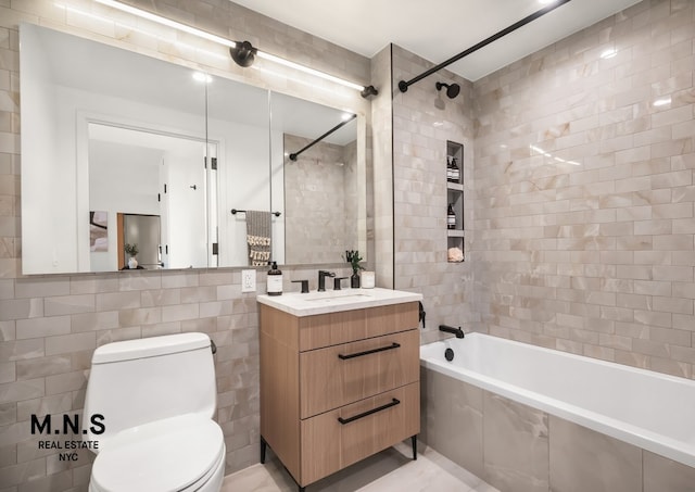 bathroom featuring toilet, tiled shower / bath, tile walls, and vanity