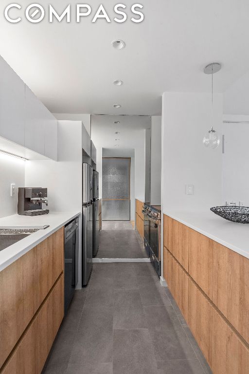 kitchen featuring white cabinetry, dishwasher, hanging light fixtures, and stainless steel refrigerator