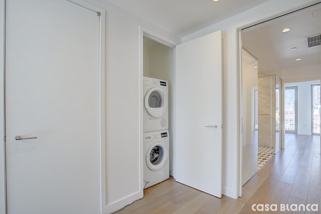 laundry area featuring light wood-type flooring, laundry area, visible vents, and stacked washing maching and dryer