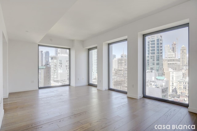 spare room featuring baseboards, wood finished floors, and a city view