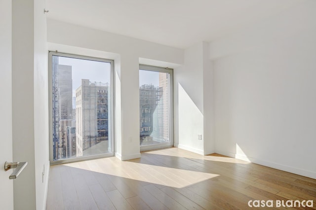 spare room with baseboards and hardwood / wood-style flooring