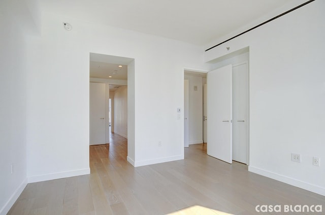 spare room with light wood-style floors and baseboards