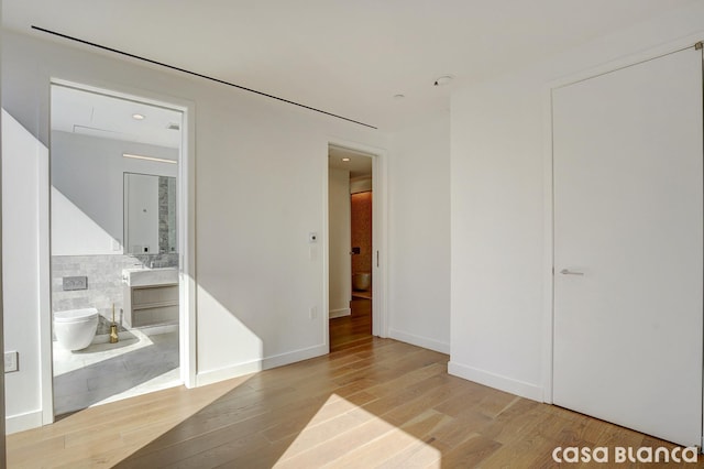 unfurnished bedroom with light wood-style flooring and ensuite bathroom