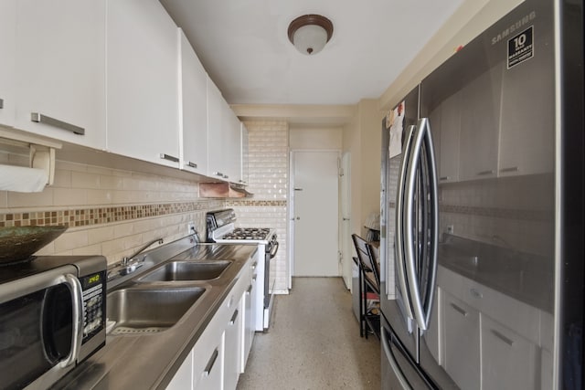 kitchen with appliances with stainless steel finishes, white cabinetry, tasteful backsplash, and a sink