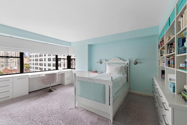 bedroom featuring light colored carpet and built in desk