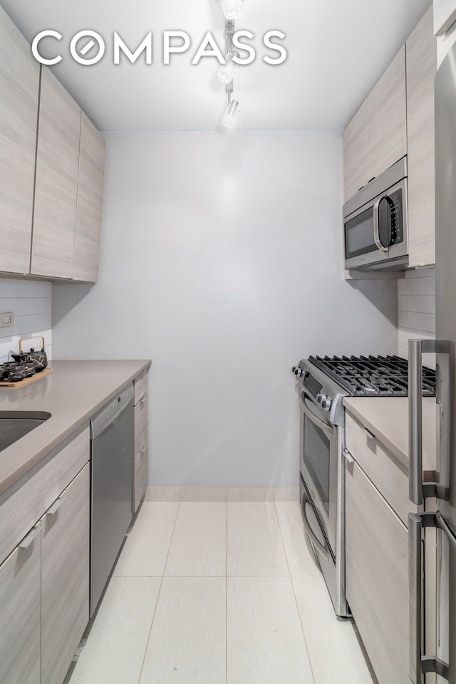 kitchen with modern cabinets, backsplash, stainless steel appliances, light countertops, and light tile patterned floors