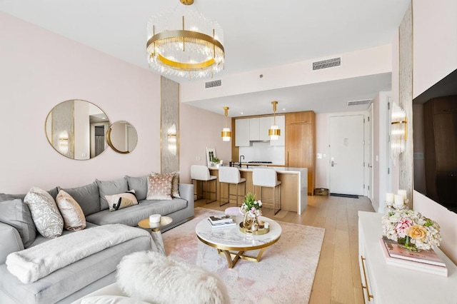 living area with light wood-type flooring, an inviting chandelier, and visible vents