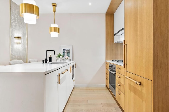 kitchen with modern cabinets, white cabinetry, pendant lighting, and light countertops