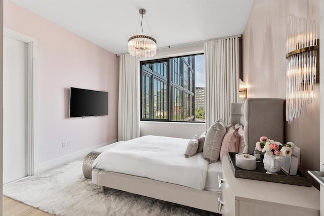 bedroom featuring an inviting chandelier, baseboards, and wood finished floors