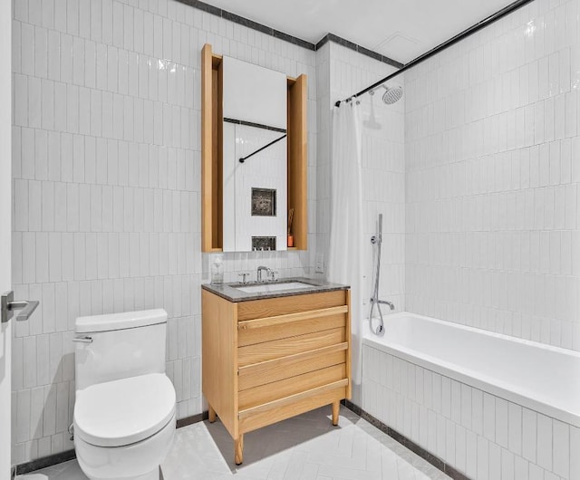 full bath with toilet, tiled shower / bath combo, vanity, and tile walls