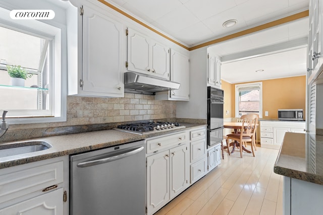 kitchen with decorative backsplash, appliances with stainless steel finishes, sink, and white cabinetry