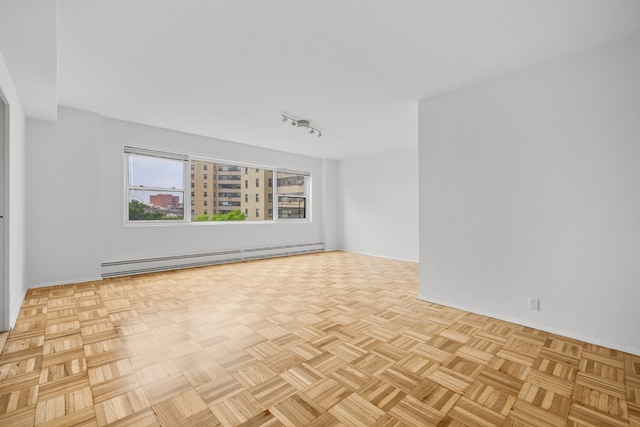 spare room featuring track lighting, light parquet flooring, and baseboard heating