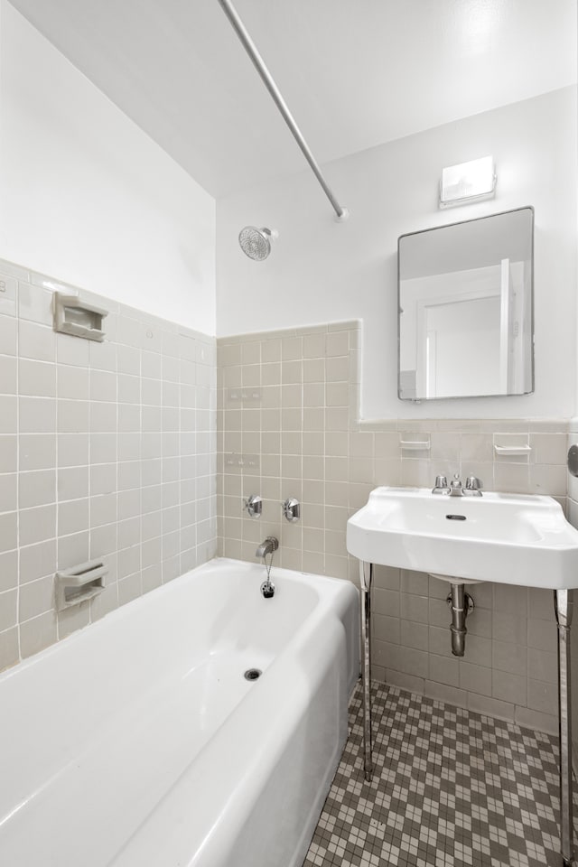 full bathroom with a wainscoted wall, a sink, and tile walls