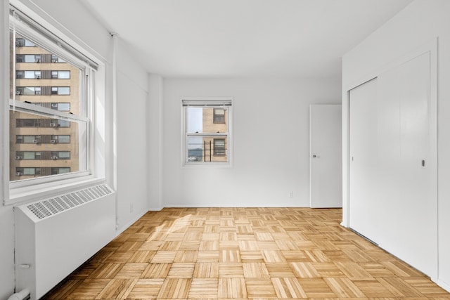 unfurnished room with radiator and light parquet floors