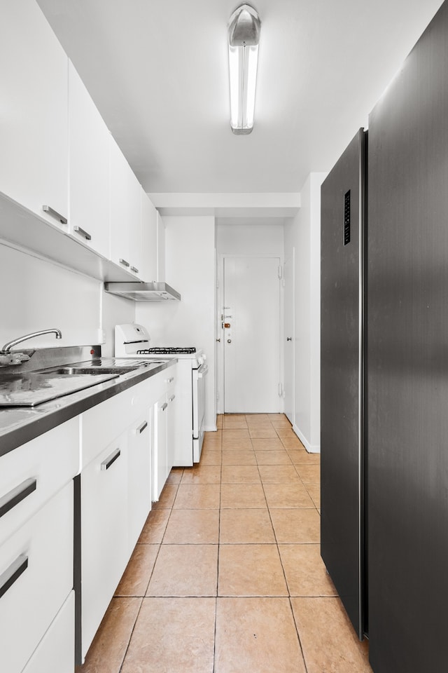 kitchen with light tile patterned flooring, a sink, white cabinets, white gas range oven, and dark countertops