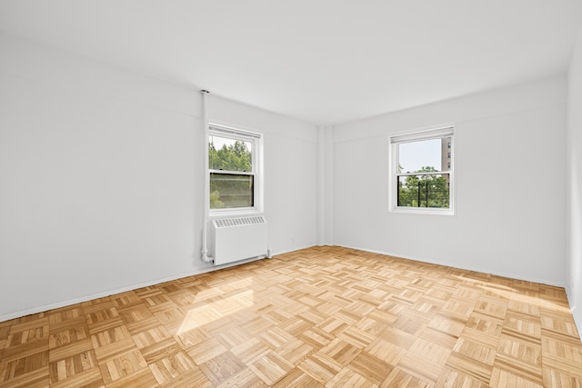 unfurnished room featuring plenty of natural light and radiator heating unit