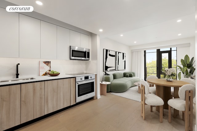 kitchen with stainless steel appliances, a sink, open floor plan, light countertops, and modern cabinets