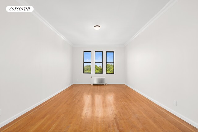 empty room featuring light wood-type flooring, crown molding, and radiator heating unit