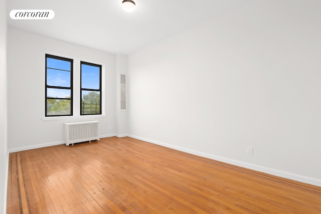 spare room with radiator heating unit and wood-type flooring