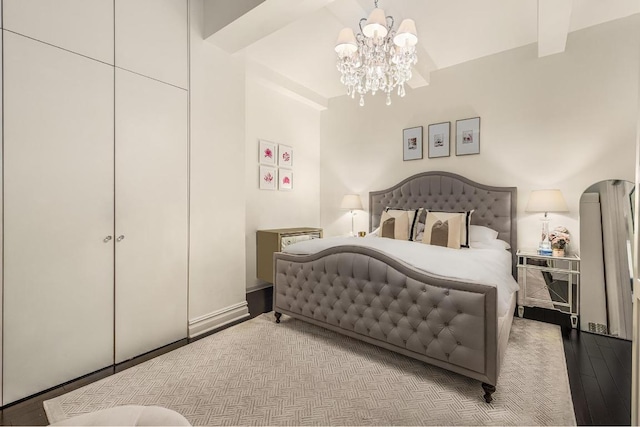 bedroom featuring a closet, beam ceiling, light hardwood / wood-style flooring, and a notable chandelier