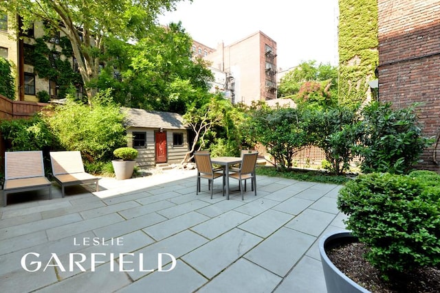 view of patio featuring entry steps, an outbuilding, and outdoor dining area