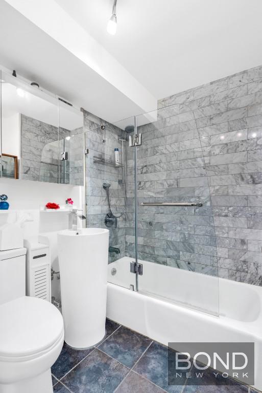 full bathroom with combined bath / shower with glass door, vanity, and toilet