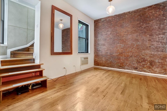 spare room with light hardwood / wood-style floors, brick wall, and a wall mounted air conditioner