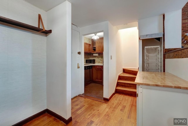 kitchen featuring decorative backsplash, dishwasher, and light hardwood / wood-style flooring