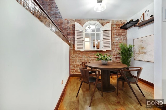 dining room with brick wall and wood-type flooring