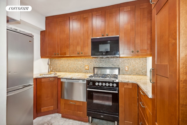 kitchen featuring sink, light tile patterned floors, light stone countertops, decorative backsplash, and black appliances